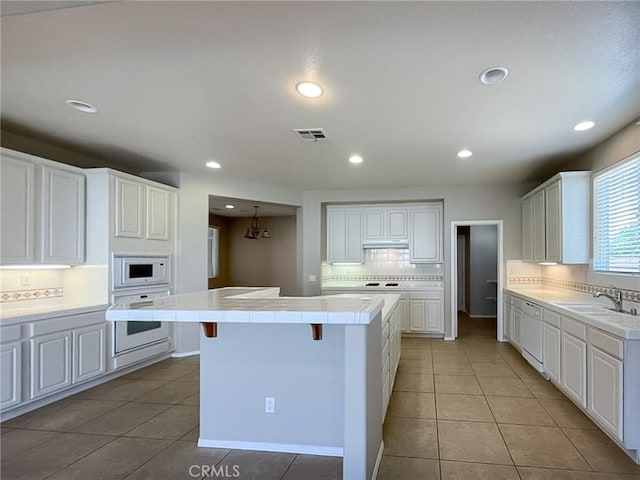 41926 Bonita Dr, Palmdale, CA 93551 - kitchen with white appliances, tile counters, tasteful backsplash, white cabinets, and recessed lighting
