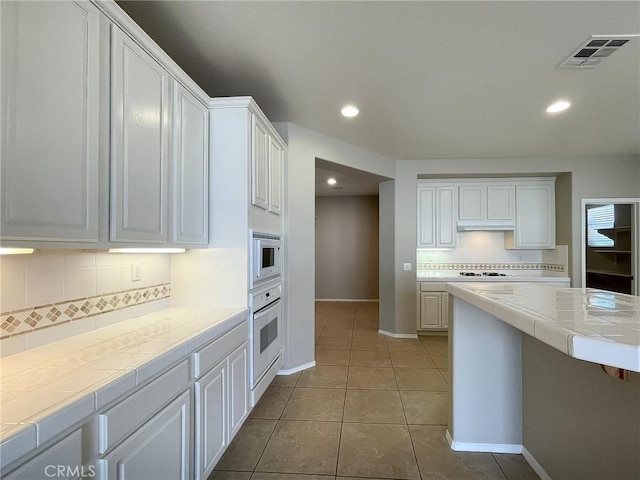 41926 Bonita Dr, Palmdale, CA 93551 - kitchen with tile countertops, white appliances, decorative backsplash, white cabinets, and tile patterned floors