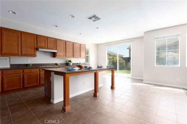 30315 Laruns St, Murrieta, CA 92563 - kitchen featuring under cabinet range hood, dark countertops, brown cabinets, tile patterned flooring, and recessed lighting