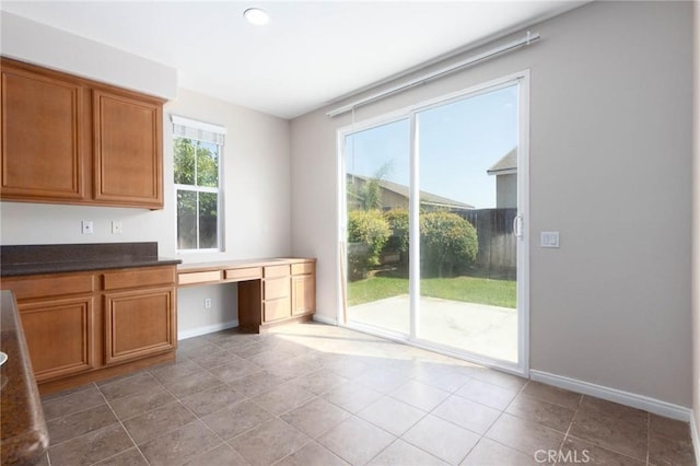 30315 Laruns St, Murrieta, CA 92563 - kitchen featuring built in study area, brown cabinetry, and dark countertops