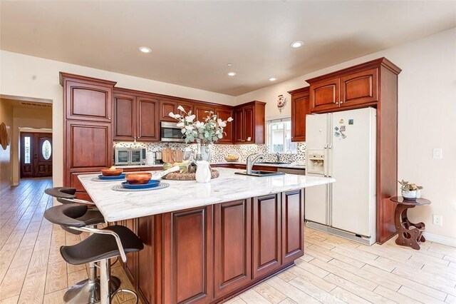 335 E Francis Ave, La Habra, CA 90631 - kitchen featuring white fridge with ice dispenser, stainless steel microwave, light wood finished floors, backsplash, and recessed lighting