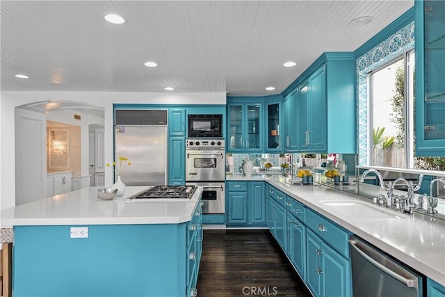 558 24th St, Hermosa Beach, CA 90254 - kitchen featuring built in appliances, blue cabinets, arched walkways, recessed lighting, and glass insert cabinets