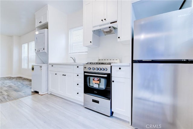 121/2 25th Pl Unit 1, Venice, CA 90291 - kitchen with stainless steel appliances, estacked washer and dryer, under cabinet range hood, light wood finished floors, and white cabinets