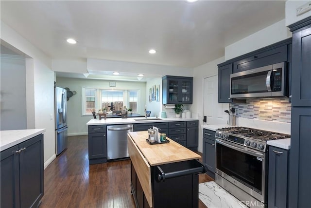 2091 Ridgeview, Corona, CA 92882 - kitchen with stainless steel appliances, decorative backsplash, a peninsula, glass insert cabinets, and dark wood-style floors