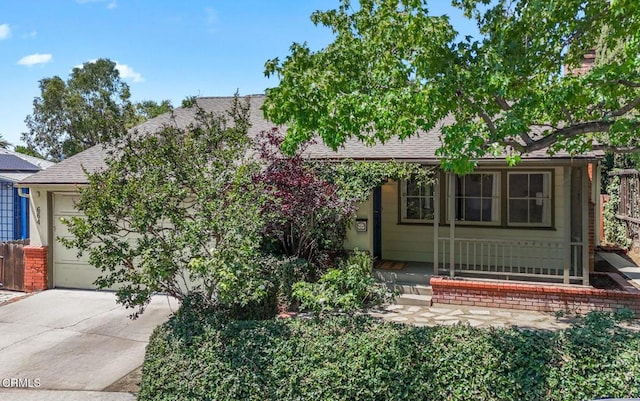 664 Monterey Rd, South Pasadena, CA 91030 - view of property hidden behind natural elements featuring roof with shingles, concrete driveway, a garage, and a porch