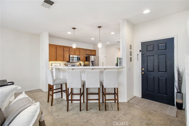 36287 Grazia Way, Winchester, CA 92596 - kitchen with appliances with stainless steel finishes, brown cabinets, a breakfast bar, light countertops, and recessed lighting