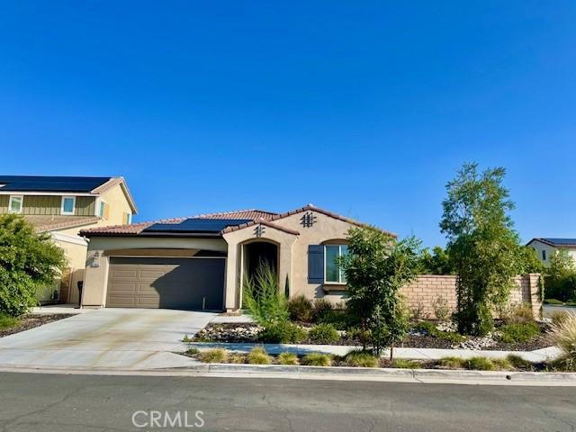 24612 Hero Cir, Menifee, CA 92584 - mediterranean / spanish-style house with stucco siding, a tiled roof, an attached garage, concrete driveway, and roof mounted solar panels