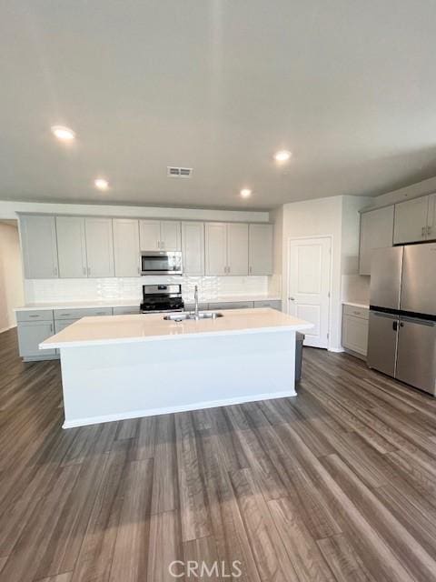 24612 Hero Cir, Menifee, CA 92584 - kitchen featuring appliances with stainless steel finishes, a kitchen island with sink, dark wood-style floors, light countertops, and recessed lighting