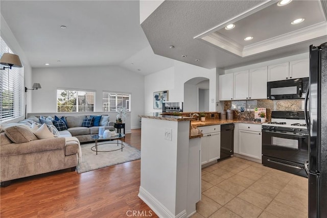 3434 E Lambeth Ct Unit F, Orange, CA 92869 - kitchen with black appliances, arched walkways, open floor plan, white cabinetry, and a peninsula