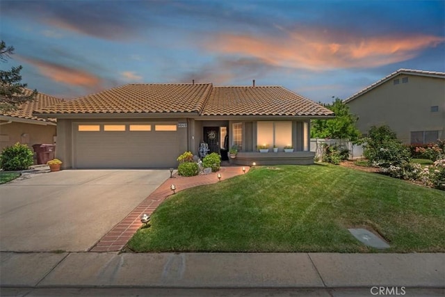 5129 W Pinehurst Dr, Banning, CA 92220 - mediterranean / spanish house with a tiled roof, an attached garage, a lawn, concrete driveway, and stucco siding