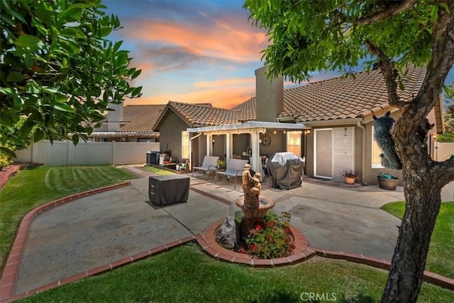 5129 W Pinehurst Dr, Banning, CA 92220 - back of property at dusk with a tile roof, stucco siding, a fenced backyard, and a patio area