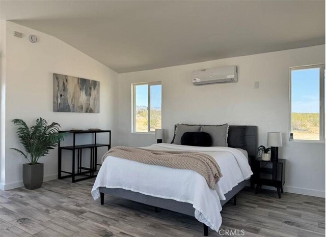 55354 El Lobo Rd, Landers, CA 92285 - bedroom featuring a wall mounted air conditioner, vaulted ceiling, wood finished floors, and multiple windows