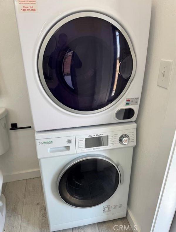 55354 El Lobo Rd, Landers, CA 92285 - laundry area with stacked washing machine and dryer and wood finished floors