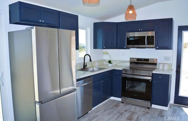 55354 El Lobo Rd, Landers, CA 92285 - kitchen featuring appliances with stainless steel finishes, lofted ceiling, blue cabinetry, light wood-style flooring, and decorative light fixtures