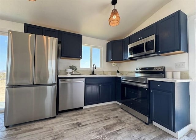55354 El Lobo Rd, Landers, CA 92285 - kitchen featuring stainless steel appliances, vaulted ceiling, light countertops, blue cabinets, and light wood-type flooring