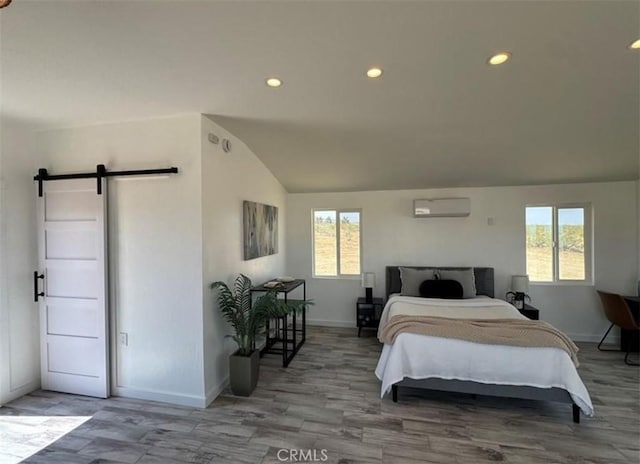 55354 El Lobo Rd, Landers, CA 92285 - bedroom with a barn door, lofted ceiling, multiple windows, a wall mounted air conditioner, and wood finished floors