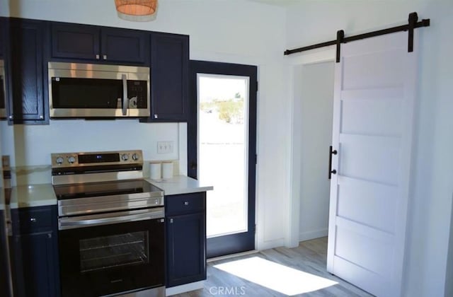 55354 El Lobo Rd, Landers, CA 92285 - kitchen featuring appliances with stainless steel finishes, a barn door, light countertops, and light wood-style floors