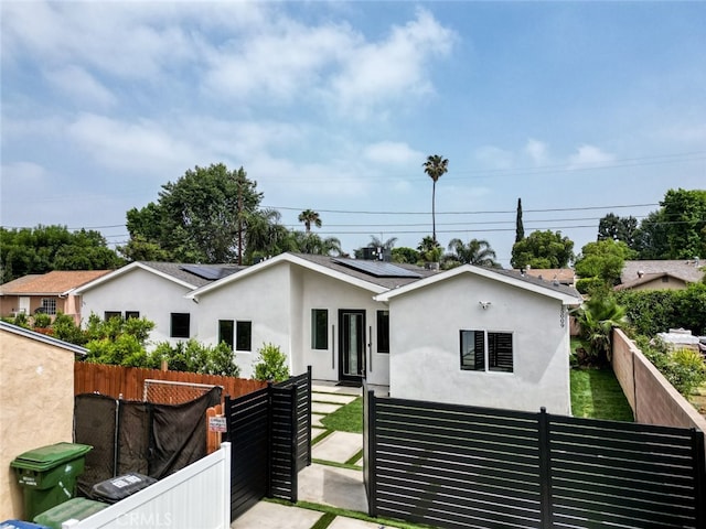 15009 Wyandotte St, Van Nuys, CA 91405 - view of front facade featuring solar panels, stucco siding, and a gate