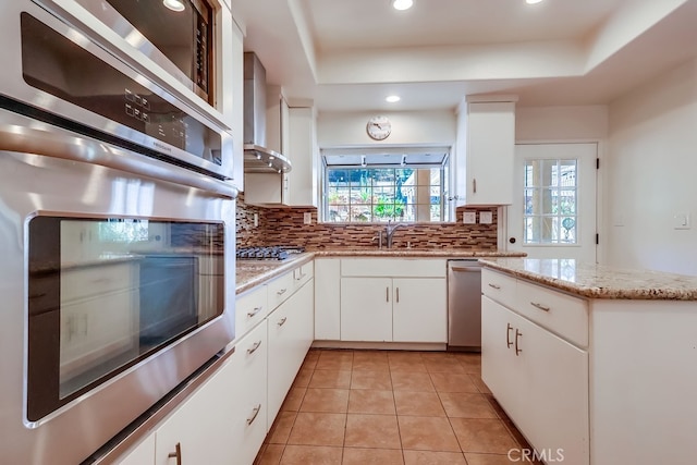 9733 Kentland Ave, Chatsworth, CA 91311 - kitchen with stainless steel appliances, tasteful backsplash, a raised ceiling, wall chimney range hood, and recessed lighting