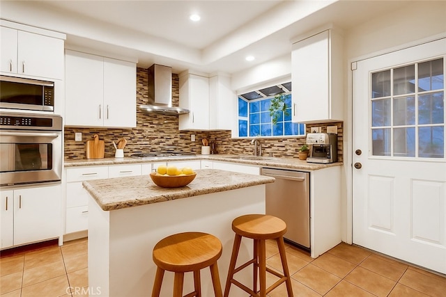 9733 Kentland Ave, Chatsworth, CA 91311 - kitchen featuring appliances with stainless steel finishes, wall chimney range hood, light tile patterned floors, a kitchen breakfast bar, and decorative backsplash