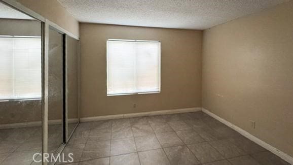 1735 E Washington St, Colton, CA 92324 - unfurnished bedroom featuring a textured ceiling and baseboards