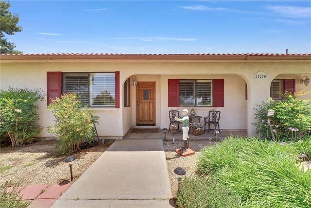 25270 Tradewinds Dr, Menifee, CA 92585 - property entrance featuring a porch and stucco siding