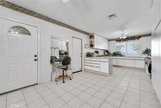 25270 Tradewinds Dr, Menifee, CA 92585 - kitchen featuring white cabinetry, a ceiling fan, a textured ceiling, a desk, and a peninsula