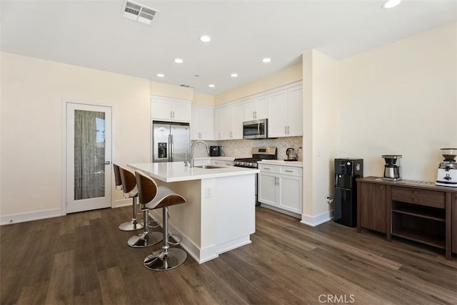 12178 Greenleaf Ln, Garden Grove, CA 92840 - kitchen featuring appliances with stainless steel finishes, dark wood finished floors, white cabinets, an island with sink, and recessed lighting