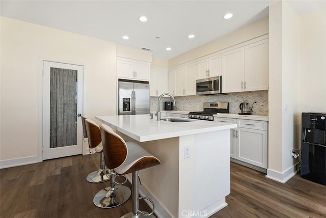 12178 Greenleaf Ln, Garden Grove, CA 92840 - kitchen featuring appliances with stainless steel finishes, dark wood-type flooring, backsplash, a kitchen island with sink, and white cabinets