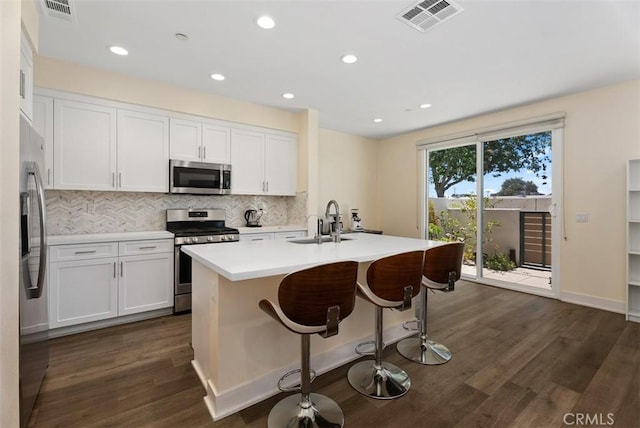 12178 Greenleaf Ln, Garden Grove, CA 92840 - kitchen with appliances with stainless steel finishes, tasteful backsplash, dark wood-style flooring, white cabinetry, and an island with sink