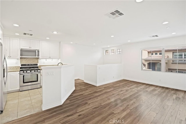 80 Hedge Bloom, Irvine, CA 92618 - kitchen featuring appliances with stainless steel finishes, light wood-style floors, recessed lighting, white cabinetry, and decorative backsplash