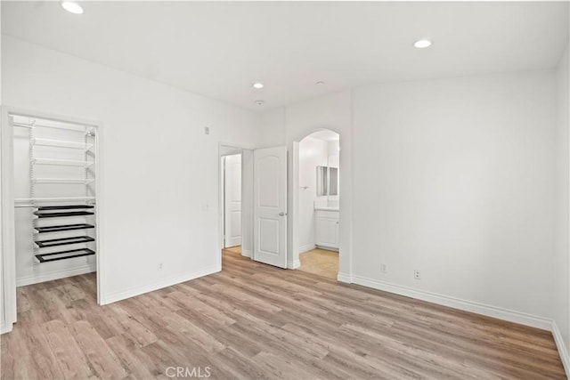 80 Hedge Bloom, Irvine, CA 92618 - unfurnished bedroom with arched walkways, light wood-style floors, recessed lighting, a walk in closet, and a closet
