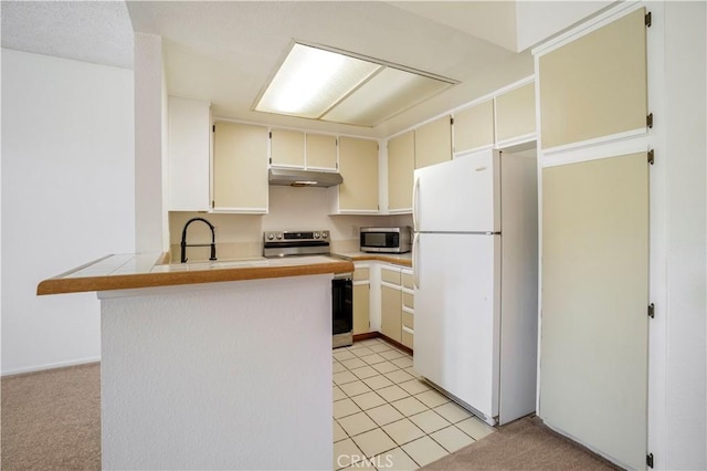 33 Abrazo Aisle Unit 174, Irvine, CA 92614 - kitchen with stainless steel appliances, under cabinet range hood, a peninsula, light carpet, and cream cabinetry