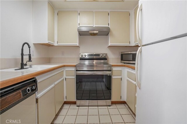 33 Abrazo Aisle Unit 174, Irvine, CA 92614 - kitchen with stainless steel appliances, under cabinet range hood, light tile patterned floors, cream cabinetry, and tile countertops