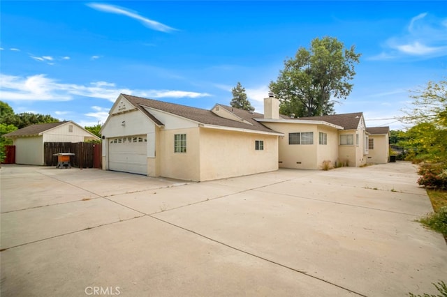 17450 Devonshire St, Northridge, CA 91325 - back of house featuring driveway, a garage, a chimney, and stucco siding