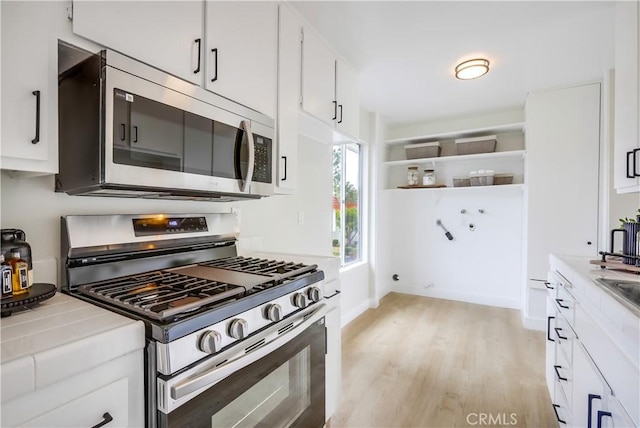 22701 Via Castilla, Lake Forest, CA 92630 - kitchen with appliances with stainless steel finishes, tile countertops, light wood-style floors, white cabinets, and open shelves