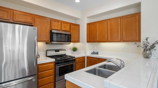 534 64th St, San Diego, CA 92114 - kitchen with stainless steel appliances, tile counters, brown cabinets, recessed lighting, and a peninsula