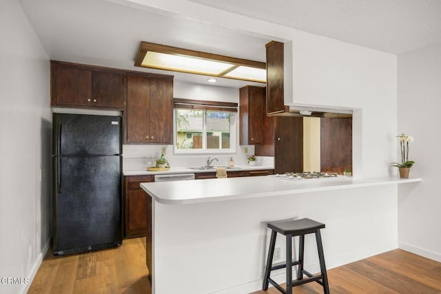 2247 Camilar Dr, Camarillo, CA 93010 - kitchen featuring freestanding refrigerator, light countertops, light wood-style flooring, a peninsula, and a breakfast bar area