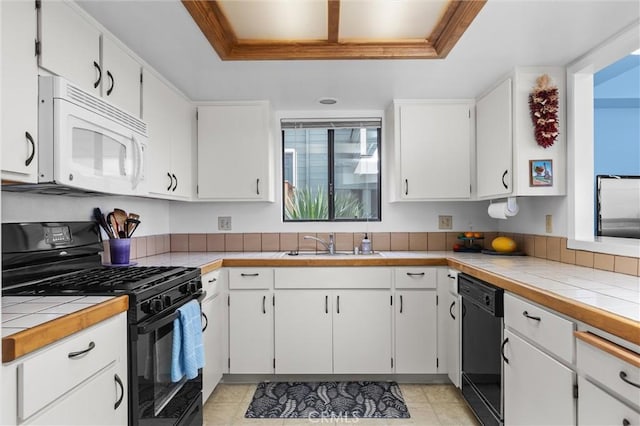 1358 Clarabelle Dr, Morro Bay, CA 93442 - kitchen with black appliances, a raised ceiling, white cabinets, crown molding, and tile countertops