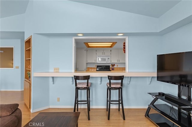 1358 Clarabelle Dr, Morro Bay, CA 93442 - kitchen featuring white microwave, range, lofted ceiling, a kitchen bar, and light wood-style floors