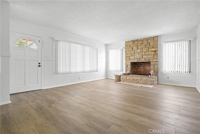 3857 W 135th, Hawthorne, CA 90250 - unfurnished living room featuring a textured ceiling, wood finished floors, and a stone fireplace