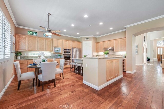 8911 Mustang Rd, Alta Loma, CA 91701 - kitchen with light brown cabinets, arched walkways, recessed lighting, a ceiling fan, and under cabinet range hood