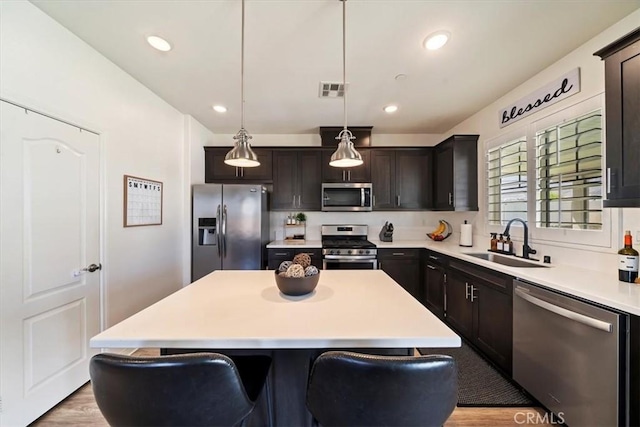 20909 Spring St, Riverside, CA 92507 - kitchen featuring appliances with stainless steel finishes, a kitchen island, light countertops, light wood-style flooring, and decorative light fixtures