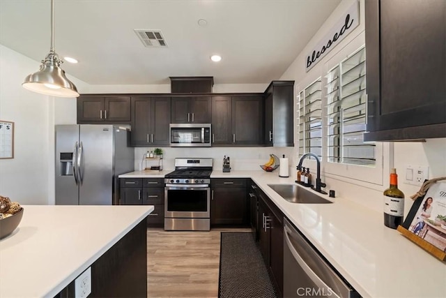 20909 Spring St, Riverside, CA 92507 - kitchen with stainless steel appliances, light countertops, light wood-style flooring, pendant lighting, and dark brown cabinets