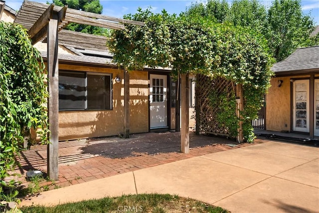 1013 Arbutus Ave, Chico, CA 95926 - doorway to property featuring roof mounted solar panels, a patio, stucco siding, and roof with shingles