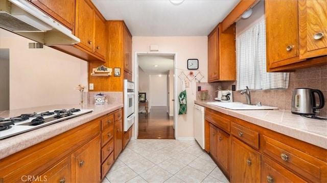 5007 Walnut Ave, Chino, CA 91710 - kitchen featuring under cabinet range hood, brown cabinets, light tile patterned flooring, and tasteful backsplash