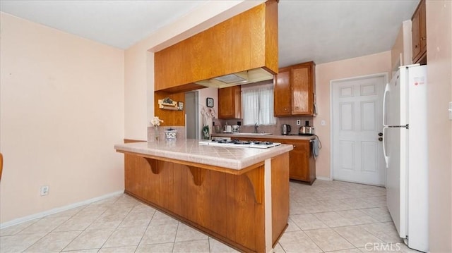 5007 Walnut Ave, Chino, CA 91710 - kitchen featuring brown cabinets, white appliances, light tile patterned floors, a peninsula, and a kitchen breakfast bar