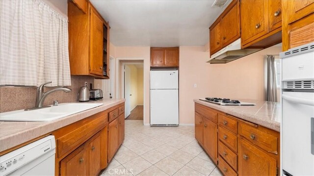 5007 Walnut Ave, Chino, CA 91710 - kitchen with white appliances, light countertops, brown cabinetry, light tile patterned floors, and decorative backsplash