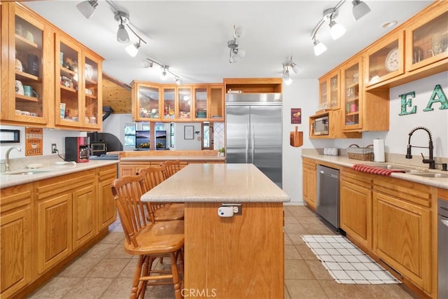 77 Park Dr, Running Springs, CA 92382 - kitchen with stainless steel appliances, a kitchen island, light tile patterned floors, glass insert cabinets, and a breakfast bar area