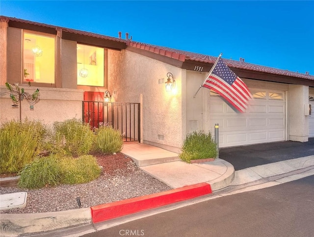 1531 Corte Caballo Unit 33, Upland, CA 91786 - view of front of property with an attached garage, stucco siding, a tile roof, and driveway